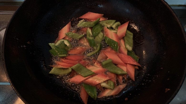 菠萝咕咾肉,锅中倒入适量的油,油热倒入胡萝卜片和青椒翻炒