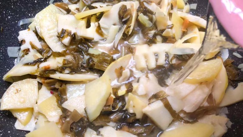 酸菜土豆烧春笋,加入适量水,大概200毫升左右,翻炒均匀,盖上盖子煮8分钟。