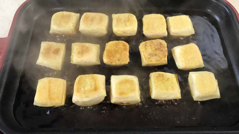 照烧豆腐,煎好后,把调好的酱汁倒入烤盘中。