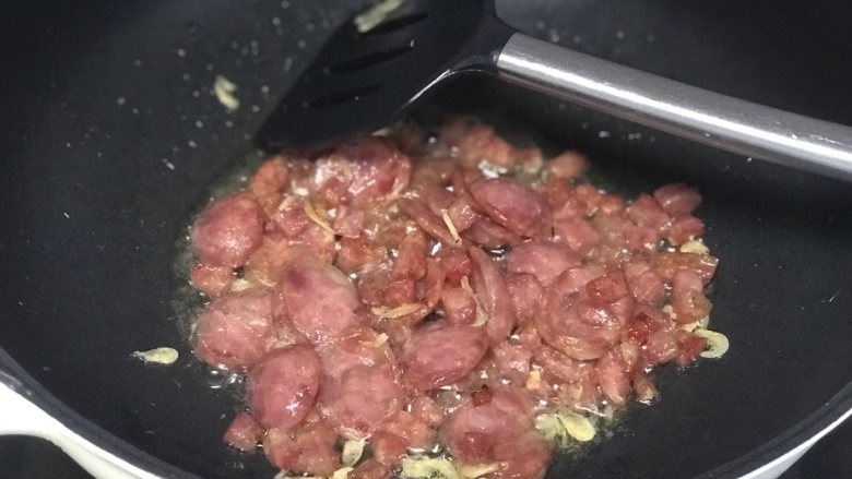腊肠焖饭,一分钟后加入海米或虾皮继续翻炒,炒至腊肠油脂逼出,全程中小火。