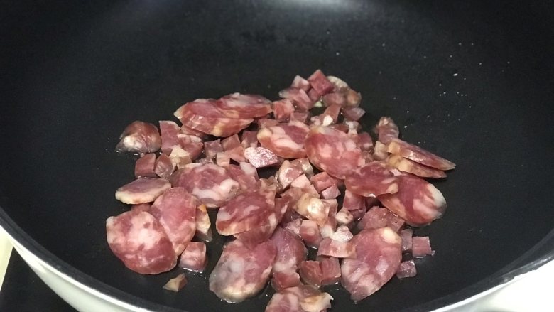 腊肠焖饭,锅内油烧热,倒入腊肠翻炒。
