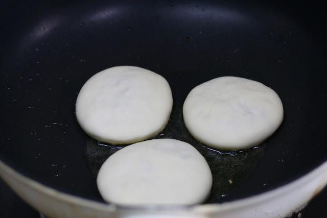 白萝卜丝馅儿饼,锅中刷一层油,把馅儿饼生坯放进去。这饼馅儿大,饼有厚度,所以要盖上锅盖来防止水分蒸发而变硬,小火烙;