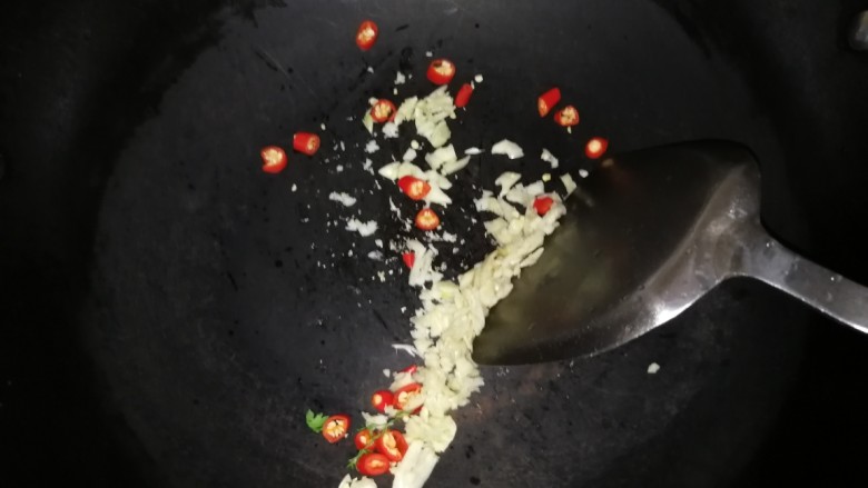 连骨头也不放过——秘制酸辣鸡爪,干锅小火,放入蒜米和辣椒圈稍微煸干水分。