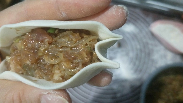 肉沫粉丝包,左手拖住。右手在顶端往里戳进去一点,然后捏住。