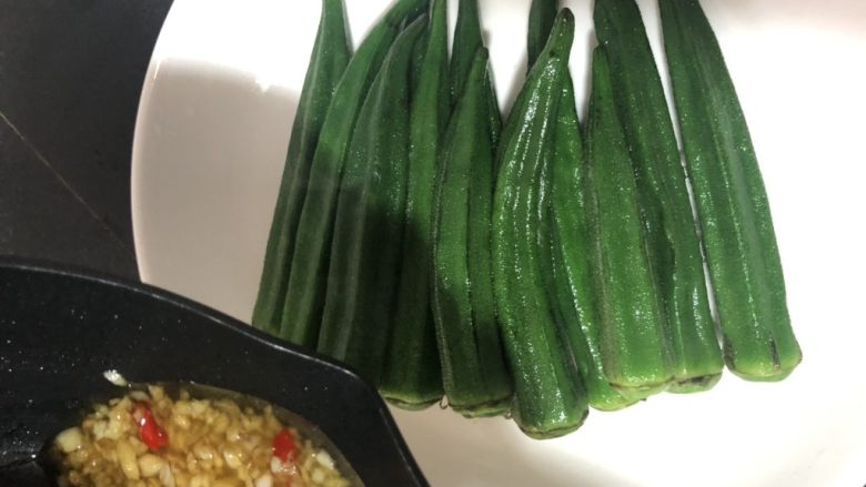 蒜蓉拌秋葵,秋葵捞起,控干水分放在干净的容器里,淋上酱汁,开胃消食的蒜蓉拌秋葵即可食用