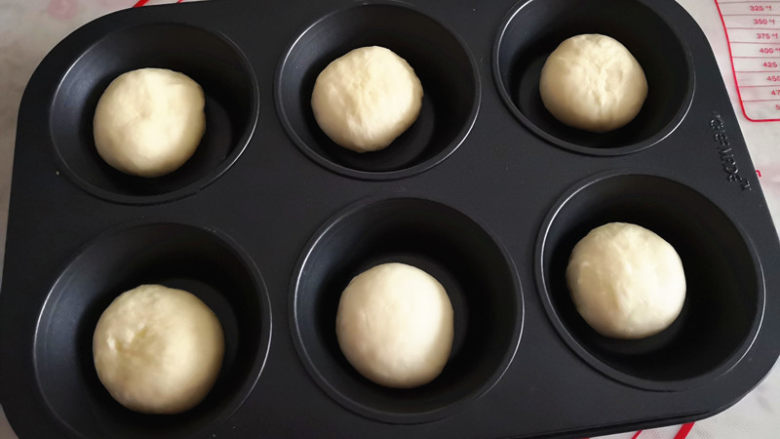 海苔芝士小餐包,六连模具如果是防粘的不用抹油,否则抹一点油防粘,将面团稍微按扁放入模具中,然后进行二次发酵,发至原来2倍大,
