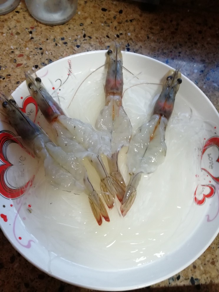家烧虾,把泡好的粉丝铺底下,再摆上处理好的虾,记得盘中要留些清水,虽然会让虾变形,但是这样的粉丝才好吃。但是水的量不能太多,不然等下装不下油会溢出来,半盘的高度就可以了