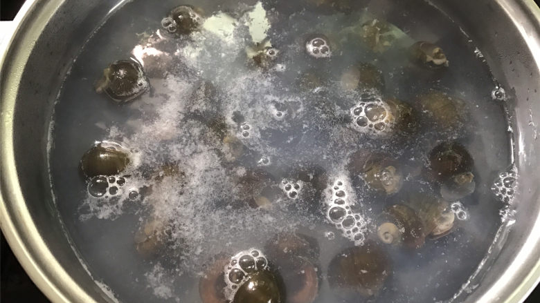 香辣田螺塞肉,锅中倒入适量清水煮开,把田螺放入锅中煮5分钟后捞出。