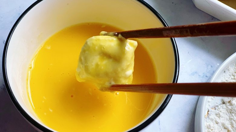 锅包豆腐,然后把滚了面粉的豆腐放入到打散的蛋液里,让每个面都裹上蛋液。裹上蛋液再煎比直接下锅煎色泽更漂亮。