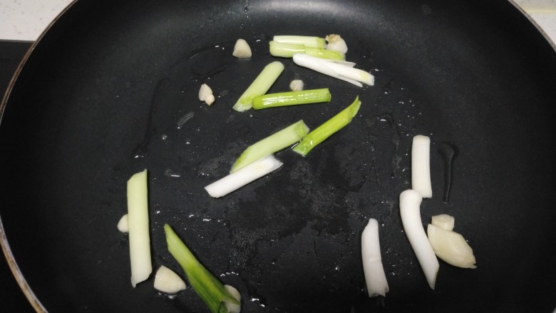 羊肉、菜椒、豆腐炒槐花骨累,锅中放入适量油，放入蒜苗跟蒜片。