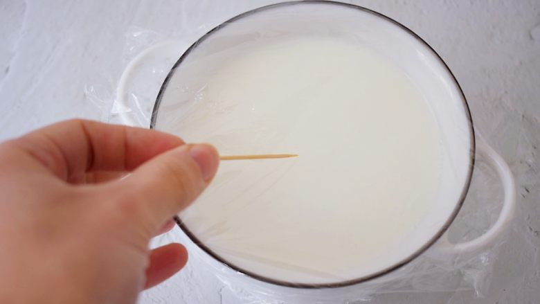 红豆双皮奶,盖上保鲜膜,用牙签在保鲜膜表面扎几个小孔