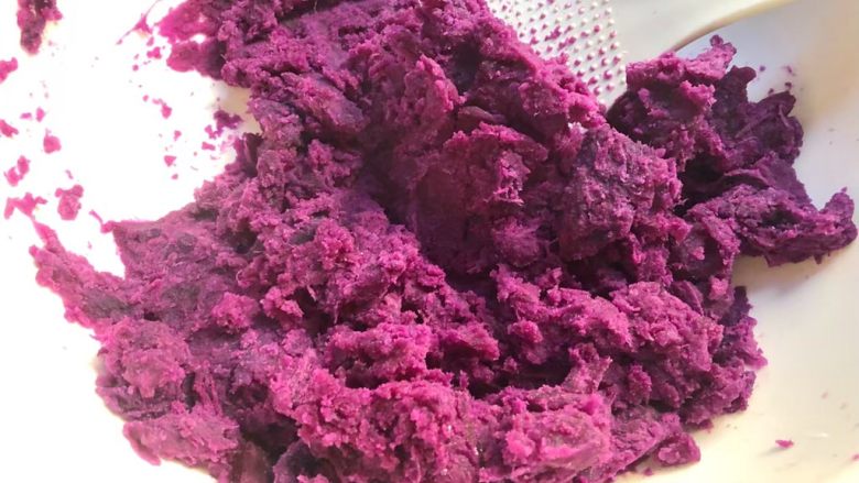紫薯糯米丸子,倒入大一点的碗里,用勺子压碎。
