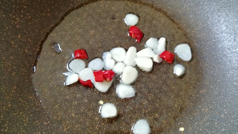 清炒茼蒿杆,锅内倒适量的食用油烧热,下入蒜片和干红辣椒炒香。