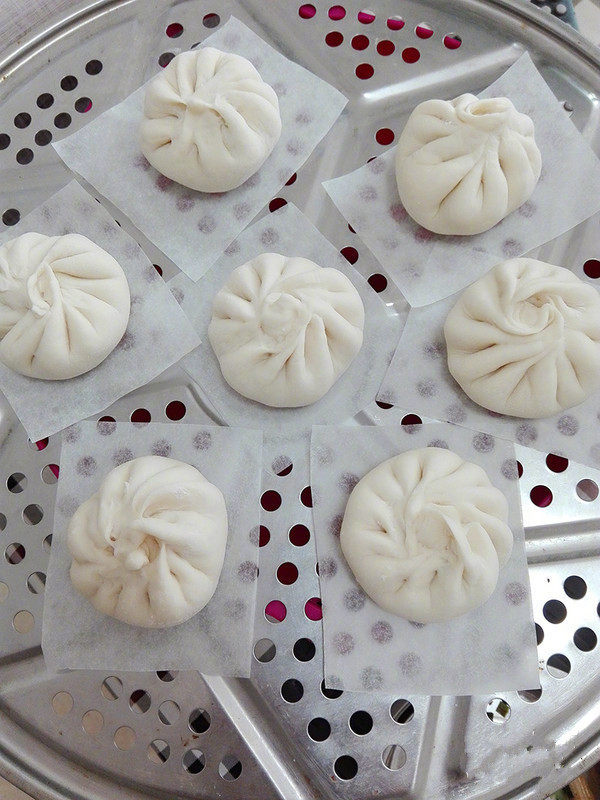 肉包子,放上油纸垫底。醒发10分钟,冷水上锅大火蒸,烧开冒蒸汽后看时间蒸15分钟左右,关火焖2分钟;