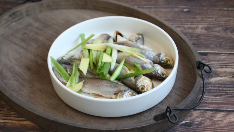 香炸小黄鱼(附炸小黄鱼酥脆的小妙招),葱姜切碎,均匀撒在鱼身上。