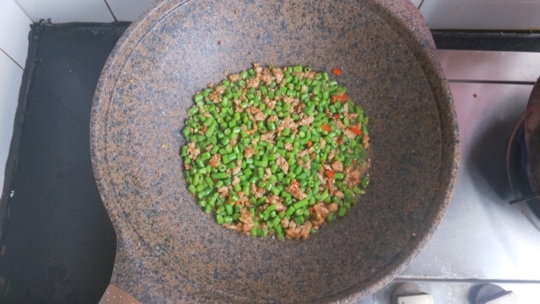 肉沫豆角,翻炒几下后,收拢到中心。加一点点水