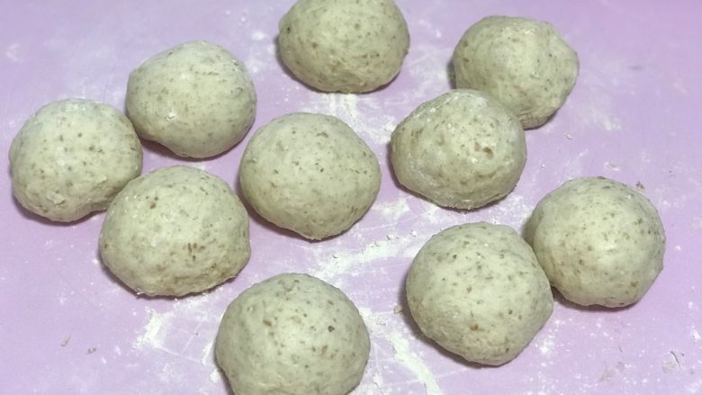 全麦奶酪果仁软欧(老面法),发好的面团轻拍排气后分成90-100克一个的面团,大概6-8个揉成圆形,盖上保鲜膜松弛20分钟。