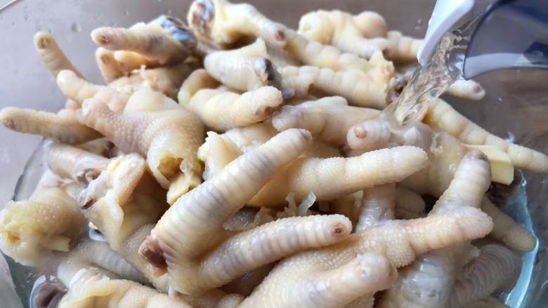 酸辣泡爪,鸡爪煮好,用漏勺捞到大碗里,加入纯净水,搅拌一下把水倒掉,再重新倒入纯净水,把鸡爪泡至完全凉透。