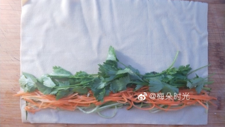 京酱肉丝,取一张豆腐皮,把黄瓜丝,胡萝卜丝,香菜各取一些摆上去