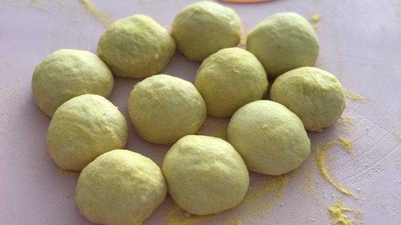 玉米面软欧,发好的面团轻拍排气后分成90克一个的面团,大概5个揉成圆形,盖上保鲜膜松弛20分钟。