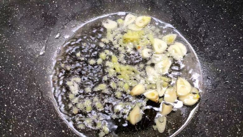 虾仁炒芦笋,热锅放入适量油,放入姜末和蒜片炒出香味。