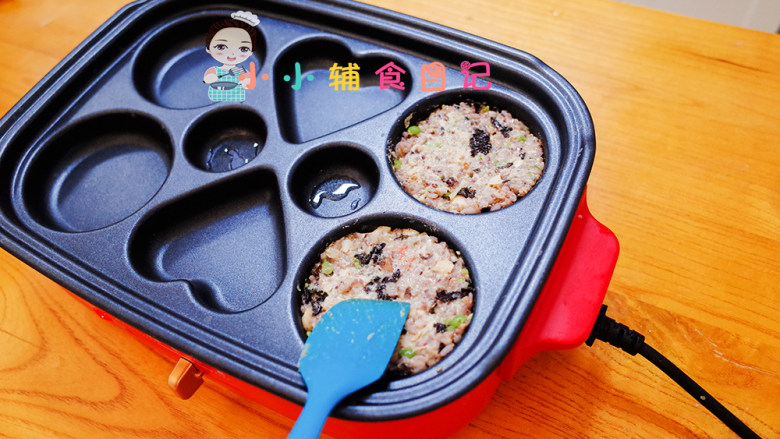 12个月以上辅食虾仁杂粮米饭饼,把做好的饭饼糊糊放入锅里,平底锅也可以,这个有性状的模具可以让饭饼更结实,用硅胶铲压一压实