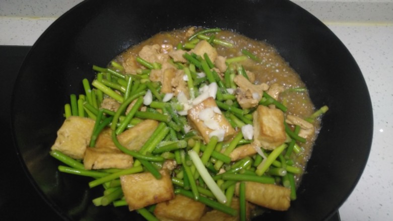 鸡肉豆腐炒蒜苔,蒜苔断生，加入适量盐、鸡精、蒜末。