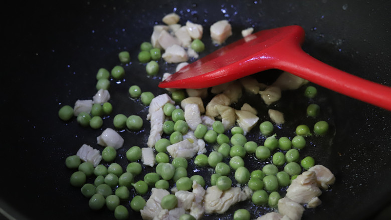 菠萝鸡丁炒饭,油锅烧热，加入鸡丁和豌豆粒炒至变色，大约为八九成熟。