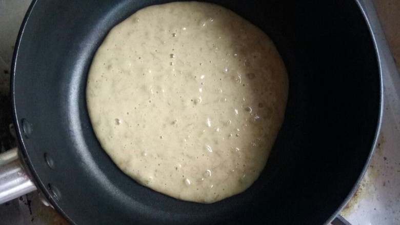 幸福西饼,舀一勺面糊在雪平锅中摊开，小火烙。