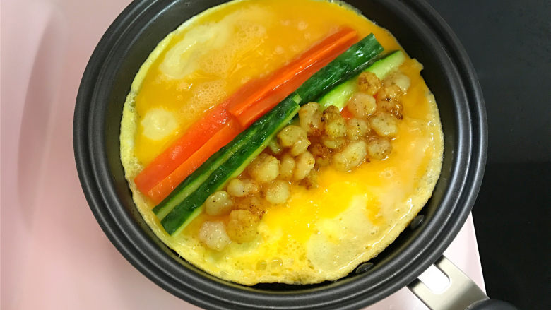 蔬菜虾仁鸡蛋饼,中小火煎至鸡蛋皮底部凝固,上面的蛋液还未凝固时把黄瓜丝、胡萝卜丝和虾仁放入。