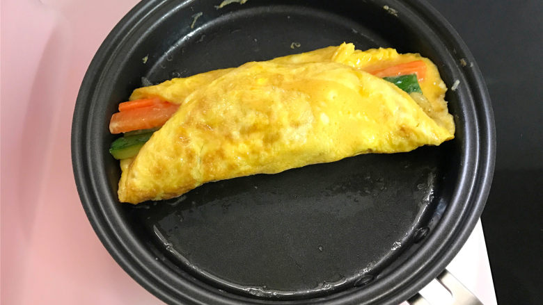 蔬菜虾仁鸡蛋饼,再把两边的蛋皮往中间折,轻轻按压后翻面后熄火。