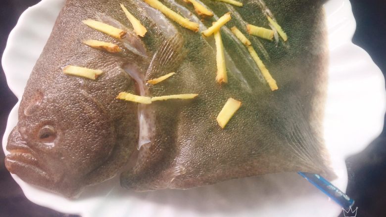 清蒸多宝鱼,锅里水开,放入鱼盘,大火蒸12分钟,倒去盘里的蒸汁,去掉鱼上的姜丝