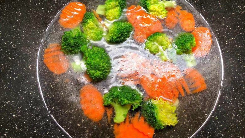 杂蔬豆腐,锅里放入适量水烧开,放入一勺油,一勺盐,少许白糖调匀,把胡萝卜和西兰花放入焯烫1分钟捞出,用冷水冲凉待用。