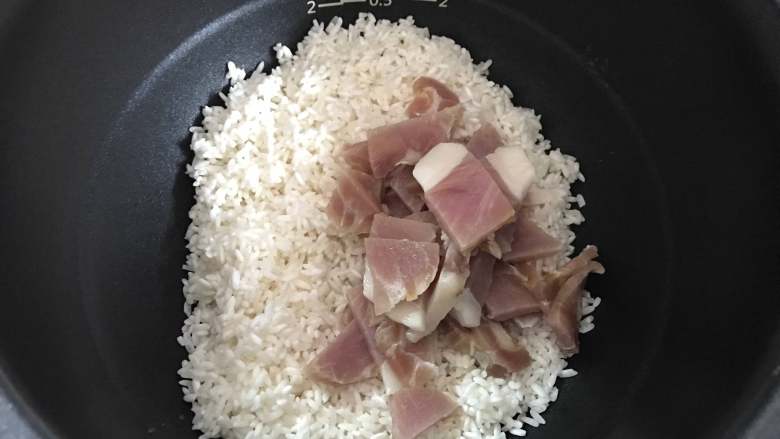 豌豆咸肉焖饭,把淘洗干净的糯米和咸肉一起放入电饭煲。