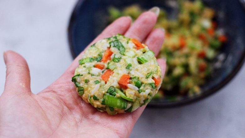 低脂杂粮谷物时蔬饼,取一块搅拌好的馅料,用手先揉圆后摁扁。