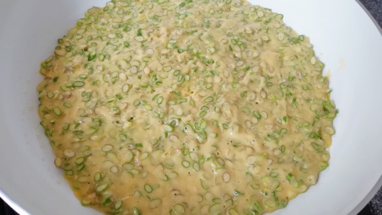 蒜苔尖鸡蛋饼,倒入蒜苔尖鸡蛋糊,用铲子摊平。