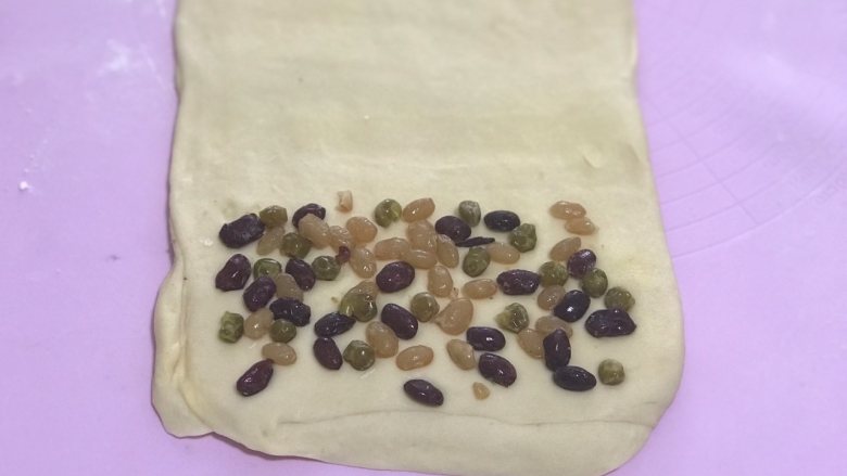 花朵蜜豆手撕吐司,步骤9的面皮旋转90度再次擀长,在底部撒上<a style='color:red;display:inline-block;' href='/shicai/ 3614'>蜜豆</a>。