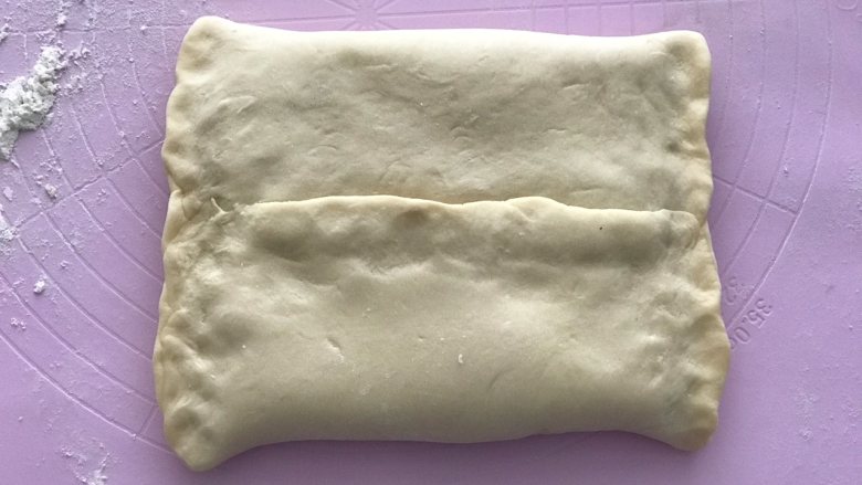 花朵蜜豆手撕吐司,将冷冻好的面皮取出再次整形擀成长度是黄油片两倍,宽度比黄油片稍宽一些,然后将黄油片如图包裹起来。