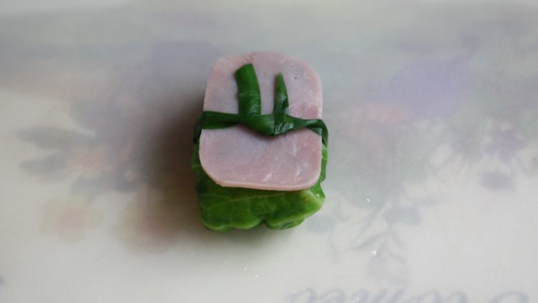 春日包菜饭便当,放上火腿片,用韭菜系上,装饰一下,包菜饭做了好了。