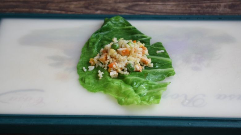 春日包菜饭便当,铺上一张焯过水的包菜,在包菜上放上适量的鸡肉什锦炒饭。