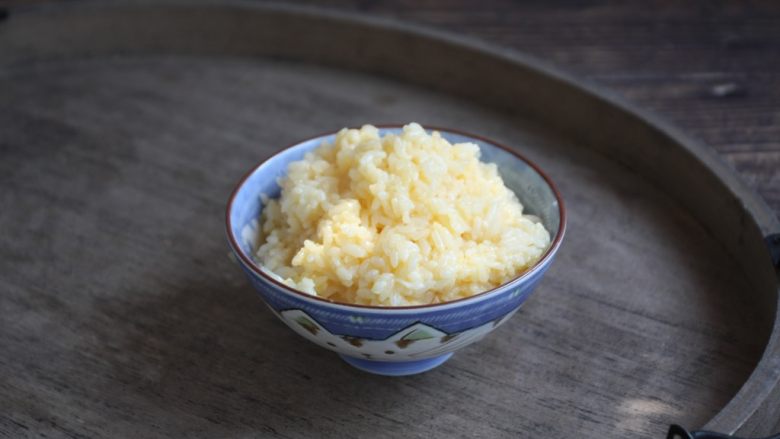 春日包菜饭便当,将米饭放在个较大的容器里,磕入一个鸡蛋,将鸡蛋和米饭抓匀备用。