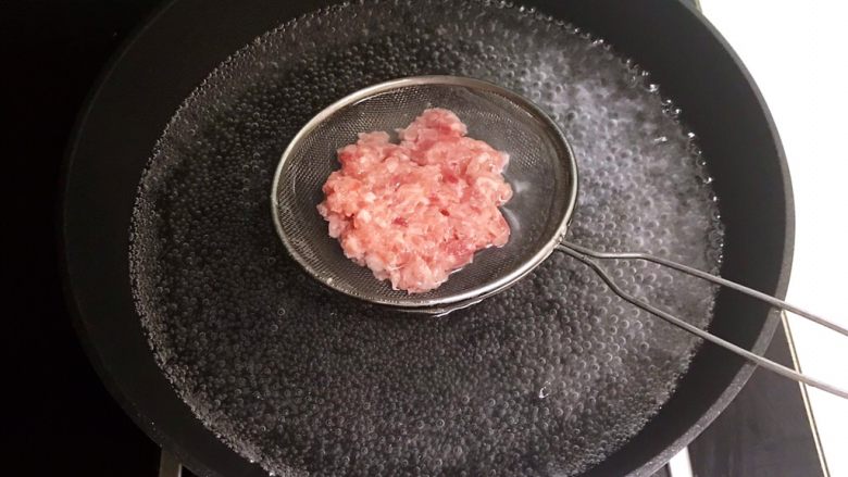 宝宝健康食谱 香葱枸杞瘦肉粥,锅里水烧开,把猪肉末连同漏勺一起放入锅里,焯水3分钟