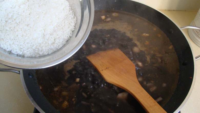 西班牙墨汁海鲜饭,倒入洗好的<a style='color:red;display:inline-block;' href='/shicai/ 492'>大米</a>搅匀铺平,开锅后中火煮至半熟