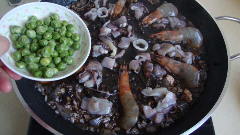 西班牙墨汁海鲜饭,放入海鲜和豌豆煮熟,收干汤汁