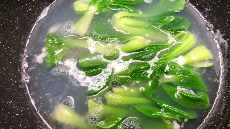 油泼面,锅里放入一勺盐,把小青菜放入烫熟。