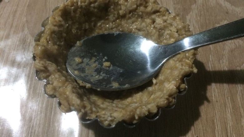 燕麦酸奶杯,准备几个蛋挞托模具,放入香蕉燕麦糊,用小勺子顺着模具边缘按压平整。压出小碗的形状,中间的坑可以压深一点;