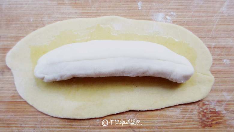仿真香蕉馒头,把白面条放在黄面皮中间。 刷油是为了隔开里外两层面皮,便于蒸好后可以轻松的剥开‘香蕉皮’