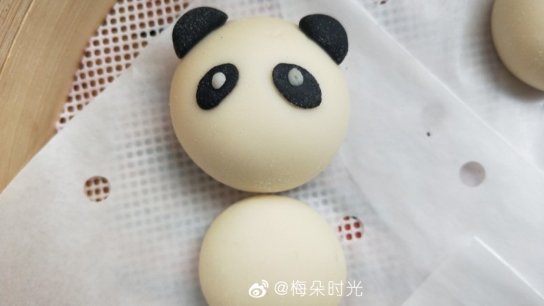 卡通馒头—小熊猫馒头,用手压扁一点,粘在面团上做它的眼睛。然后用白色面团做一个很小很小的圆粘上去做眼珠。