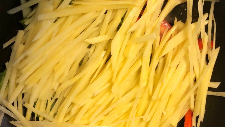 青椒土豆丝,倒入土豆丝翻炒至变软。