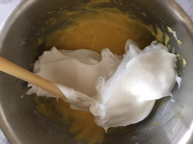蛋糕界的网红--古早蛋糕,用刮刀铲出三分之一蛋白加入蛋黄糊中,像炒菜一样翻拌均匀,然后把蛋黄糊倒入剩余的蛋白中,继续翻拌均匀,大幅度快速温柔的翻拌,以防消泡哦。